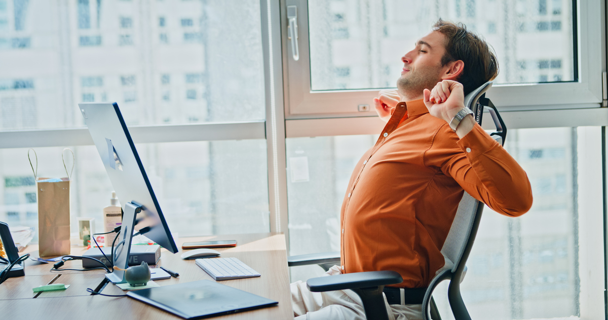 muž si protahuje záda vsedě na židli v kanceláři