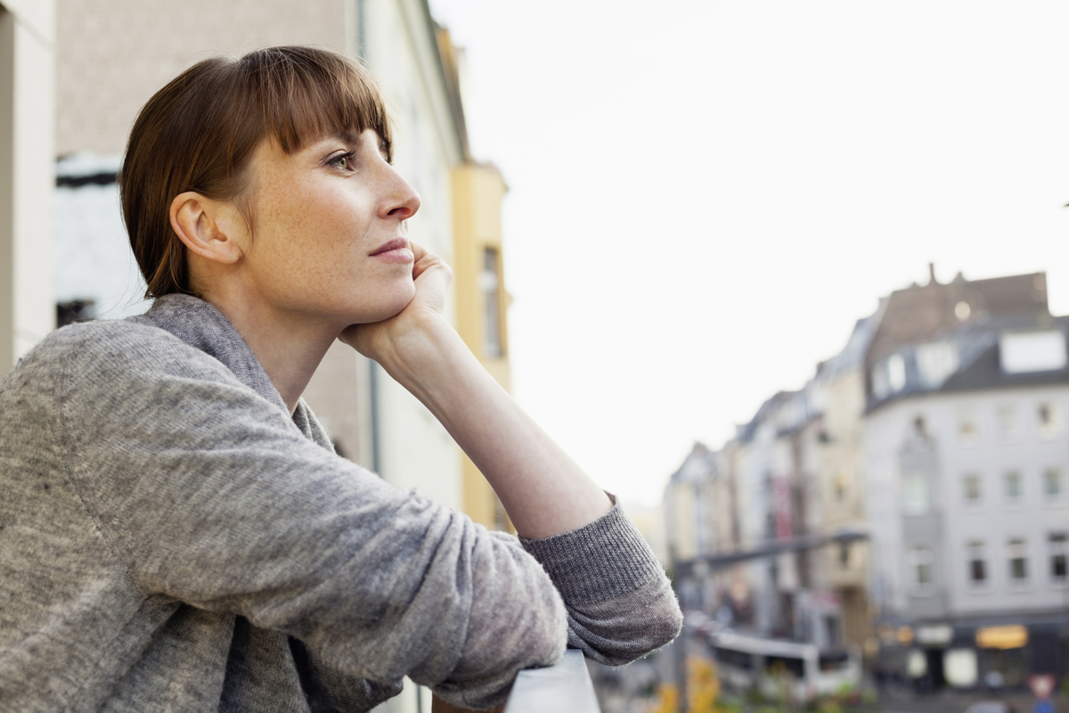prokrastinující žena vyhlíží z okna