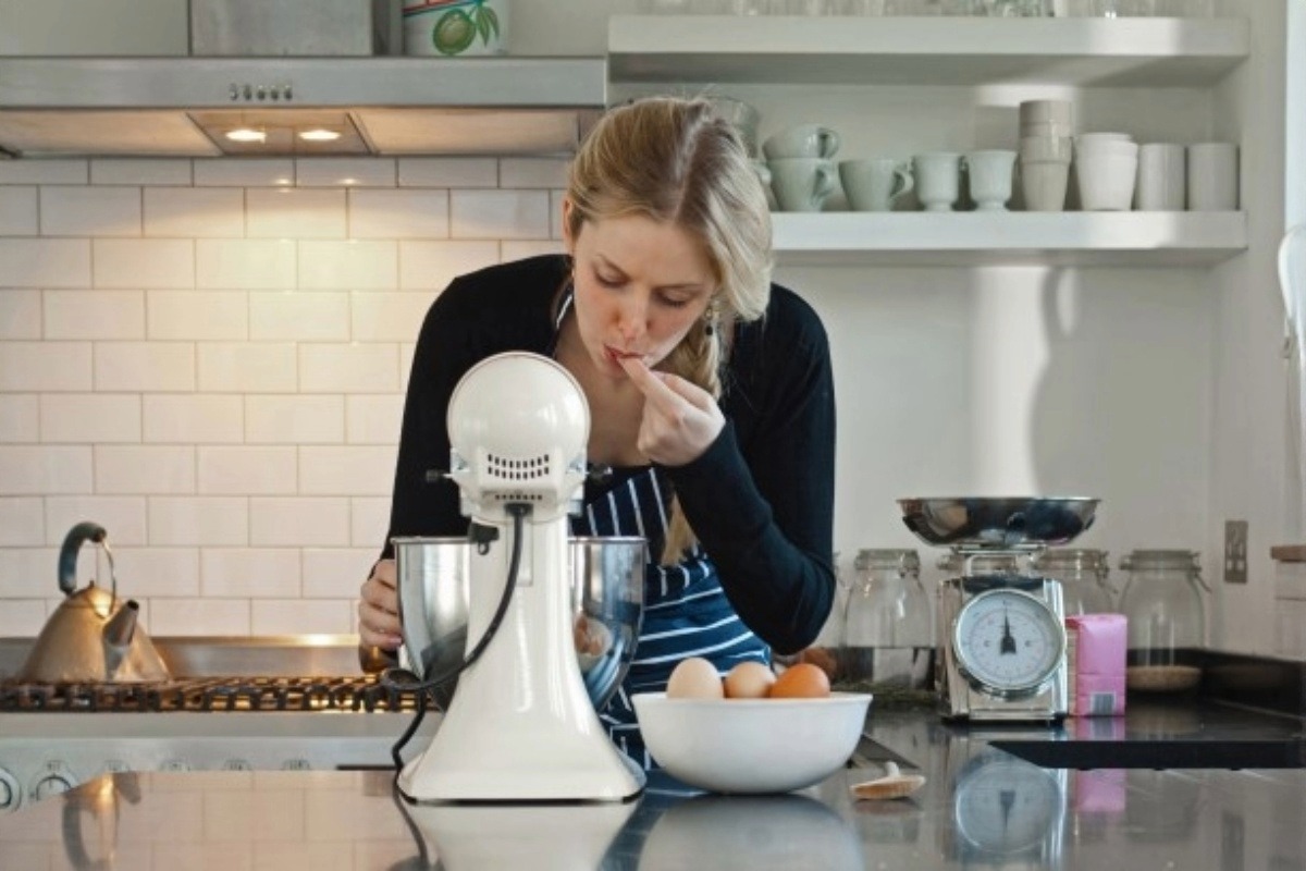 žena dělá těsto na pečení a přitom jej ochutnává