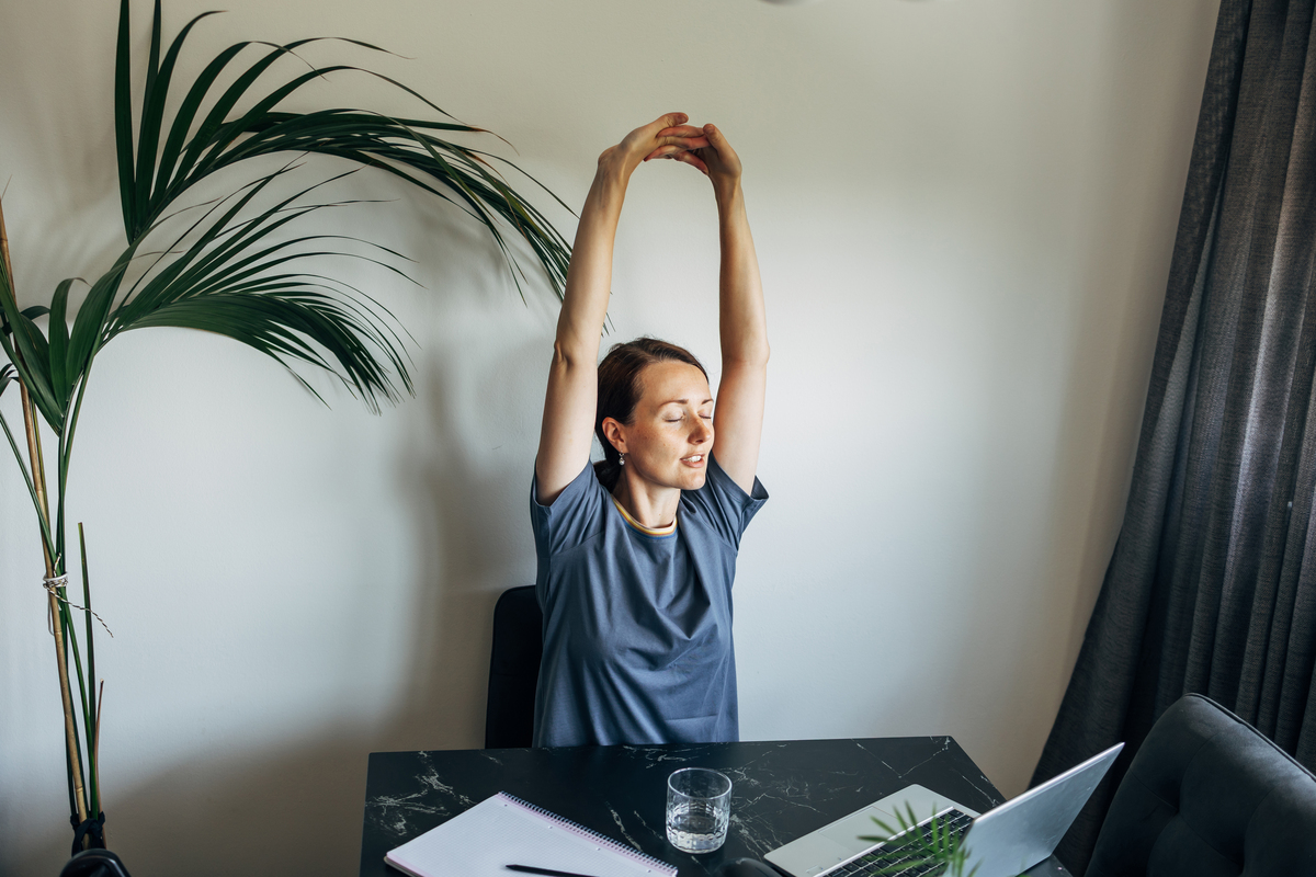 mladá žena se protahuje při práci u počítače