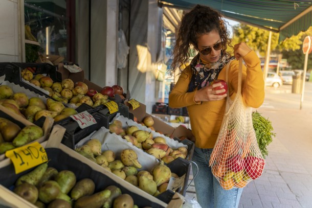 Žena nakupuje ve stánku s ovocem a zeleninou.