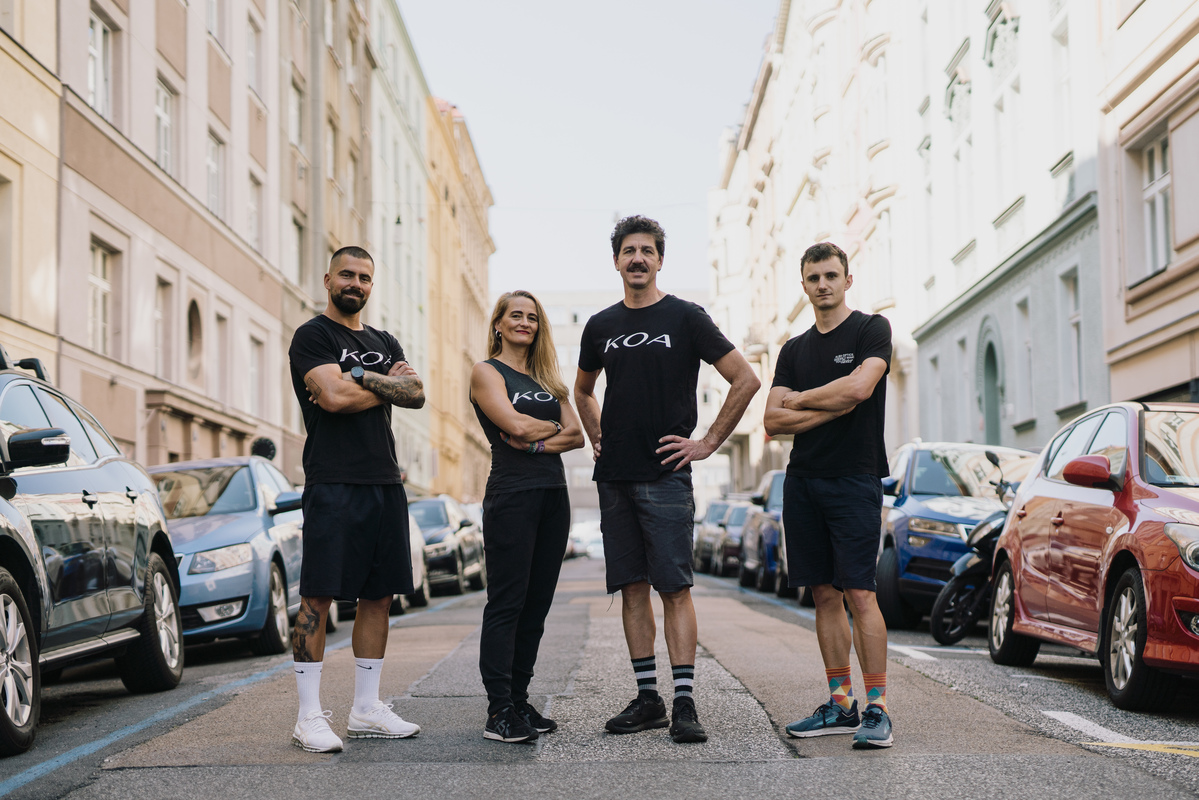 trenéři KOA stojící uprostřed ulice s obrandovanými tričky s nápisem KOA