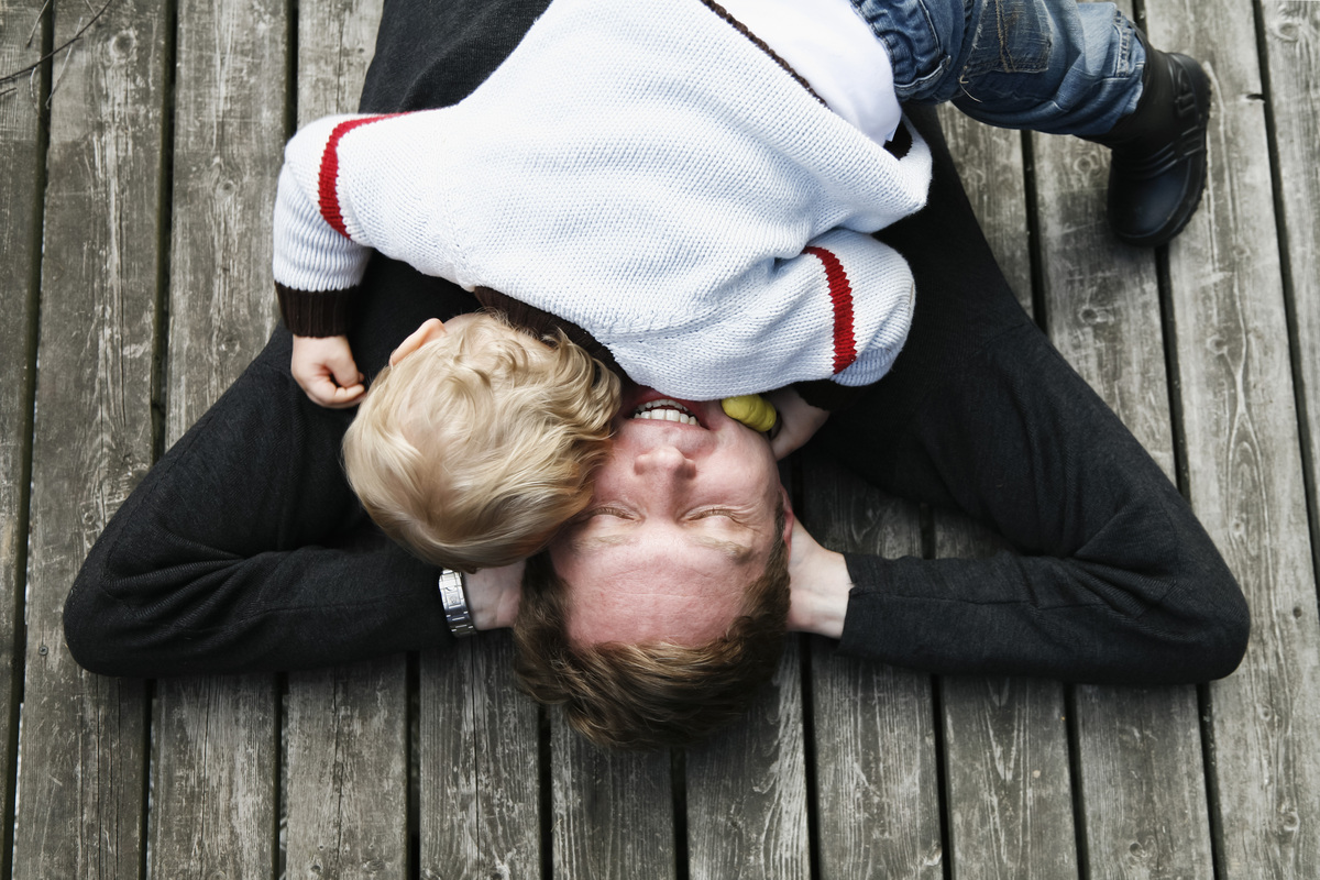 otec leží na zádech s rukami za hlavou a malé dítě leží spokojeně na něm