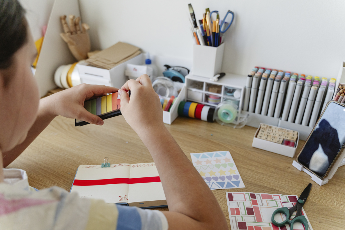 dítě sedí u pracovního stolu a lepí