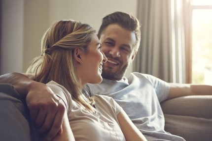 mlada rodina Pojištěný a šťastný mladý pár sedí v objetí na sedačce