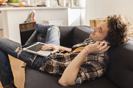 student Pojištěný student leží na pohovce a poslouchá hudbu
