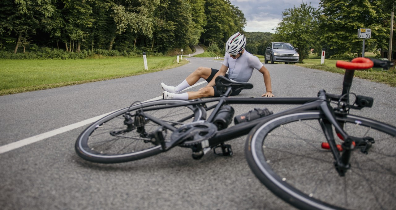 Zraněný cyklista po pádu na silnici.